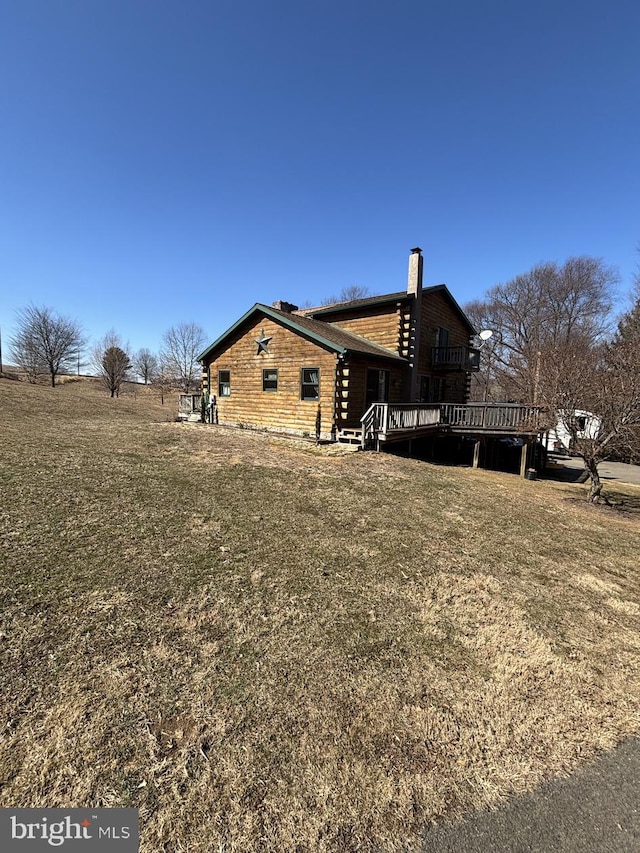 back of property featuring a yard, a chimney, and a wooden deck