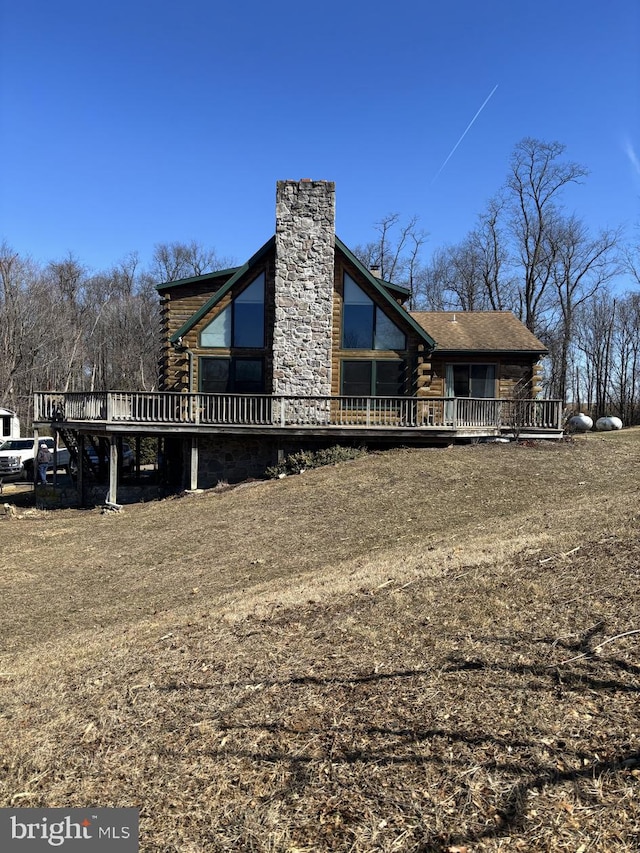 view of side of home featuring log siding, a deck, and a chimney