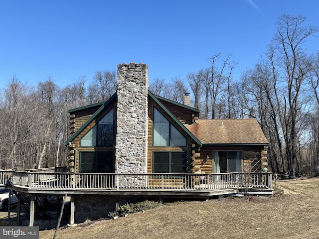 exterior space featuring a wooden deck, log exterior, and a chimney