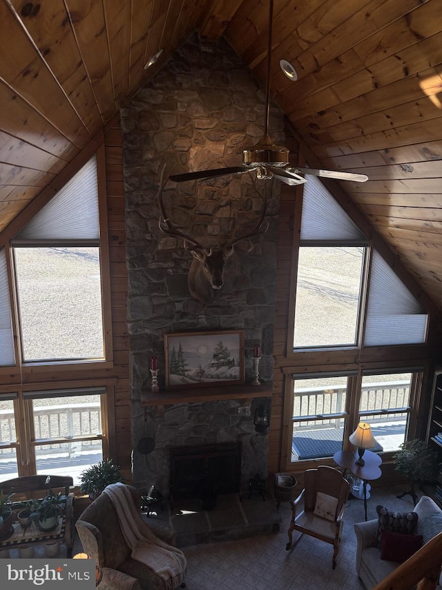 unfurnished living room featuring a stone fireplace, a healthy amount of sunlight, wood ceiling, and a ceiling fan