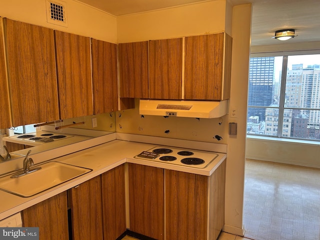 kitchen with under cabinet range hood, brown cabinets, and white electric stovetop