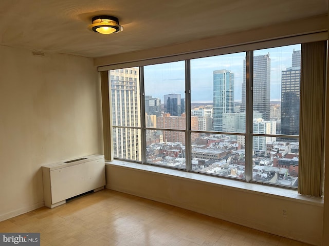 unfurnished room featuring a view of city and radiator heating unit