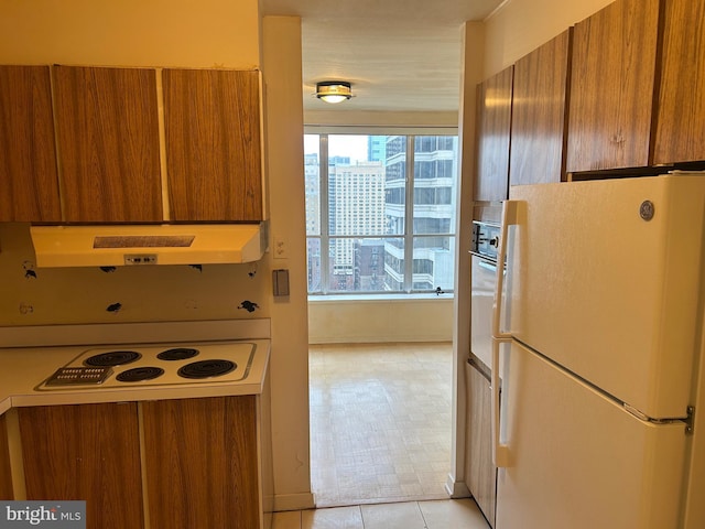 kitchen with white appliances, brown cabinetry, and under cabinet range hood