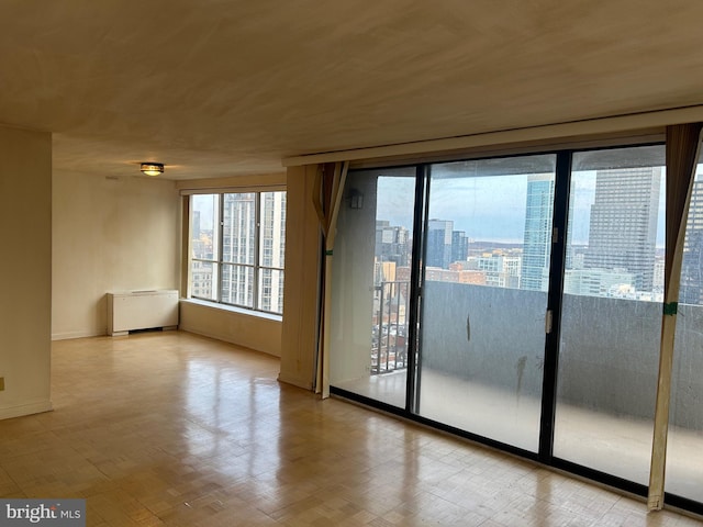 spare room with baseboards, a view of city, and radiator heating unit