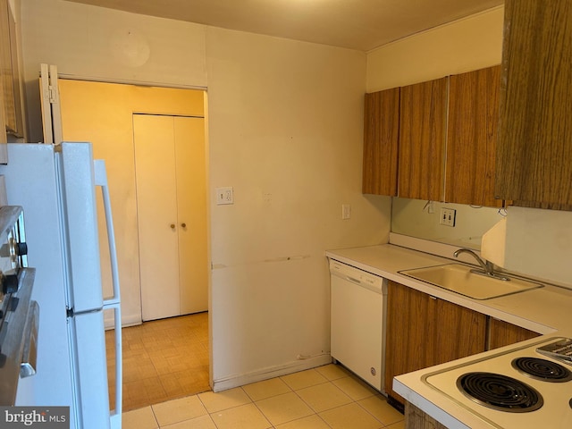 kitchen with white appliances, brown cabinetry, light countertops, and a sink