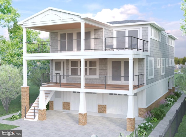 view of front of home with decorative driveway, a garage, a balcony, stairs, and a patio area