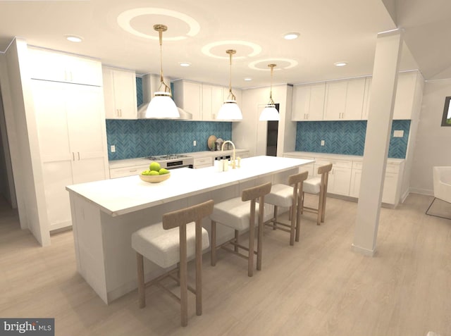 kitchen featuring light countertops, a kitchen breakfast bar, white cabinetry, wall chimney exhaust hood, and a kitchen island with sink