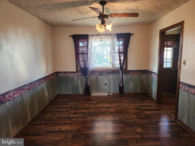 unfurnished dining area featuring wood finished floors, a healthy amount of sunlight, ceiling fan, and wainscoting