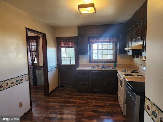 kitchen with dark wood-type flooring, under cabinet range hood, light countertops, white range with electric stovetop, and a sink