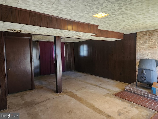 finished below grade area featuring a wood stove and wooden walls