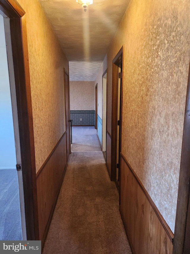 hall featuring wallpapered walls, carpet flooring, and a wainscoted wall