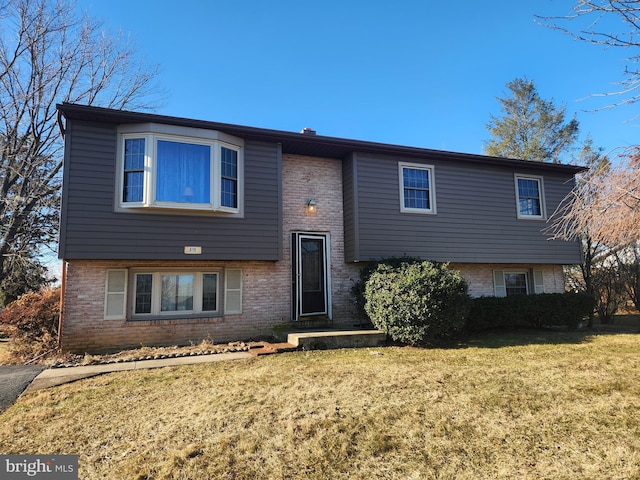 split foyer home featuring brick siding and a front lawn