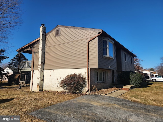 view of property exterior featuring a lawn, brick siding, and a chimney