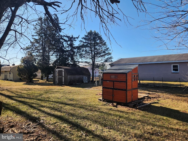 view of yard featuring a storage unit, an outdoor structure, and fence