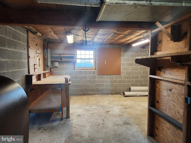 basement featuring a workshop area, heating fuel, and concrete block wall