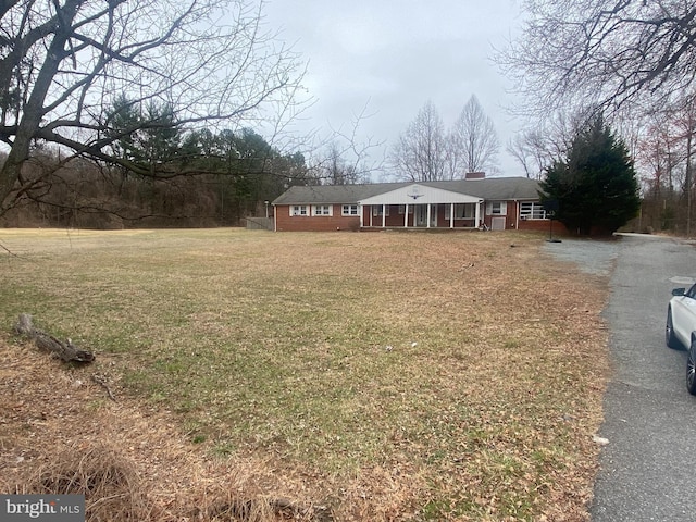 single story home with aphalt driveway, a chimney, and a front yard