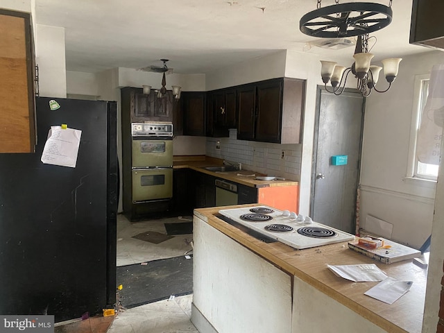 kitchen featuring multiple ovens, a notable chandelier, freestanding refrigerator, white electric stovetop, and dishwashing machine