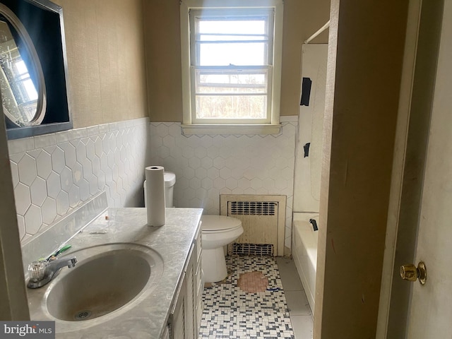 full bathroom featuring a wainscoted wall, toilet, vanity, radiator heating unit, and tile walls