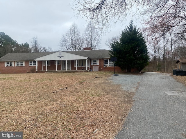 ranch-style house with aphalt driveway, a porch, and brick siding