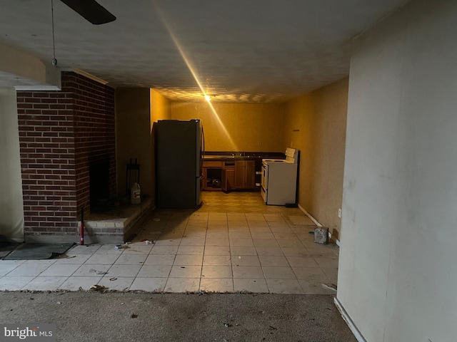 finished basement with light colored carpet and freestanding refrigerator