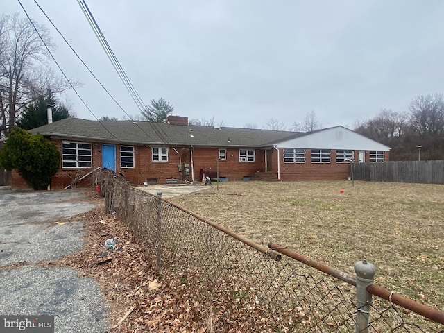 back of house with entry steps, fence, brick siding, and a chimney