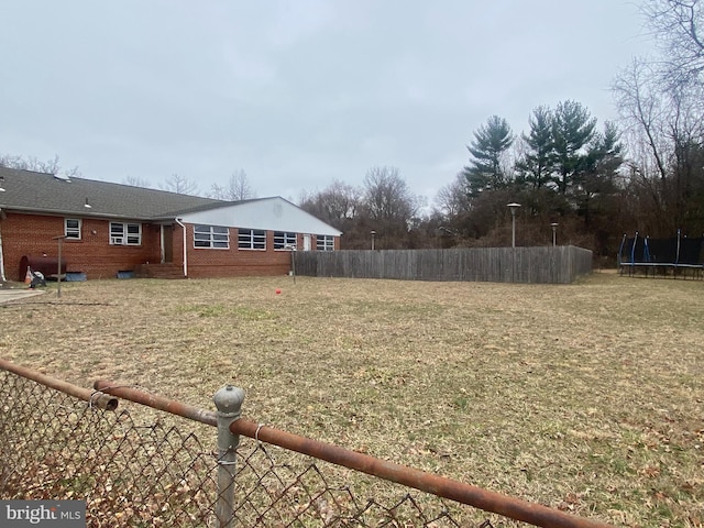 view of yard with a trampoline and fence