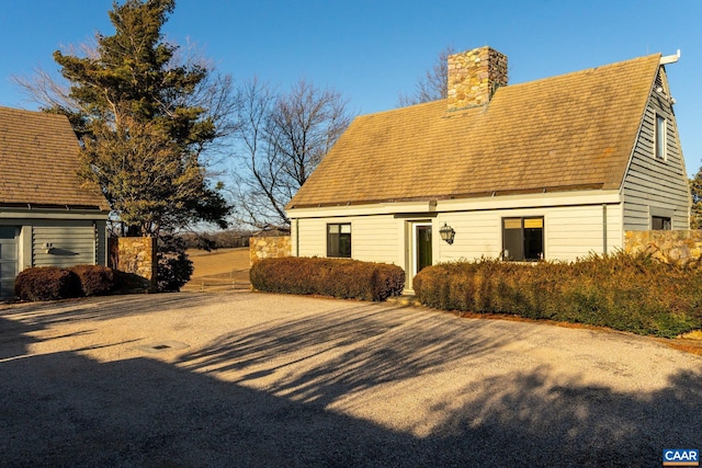 view of home's exterior featuring a chimney and roof with shingles