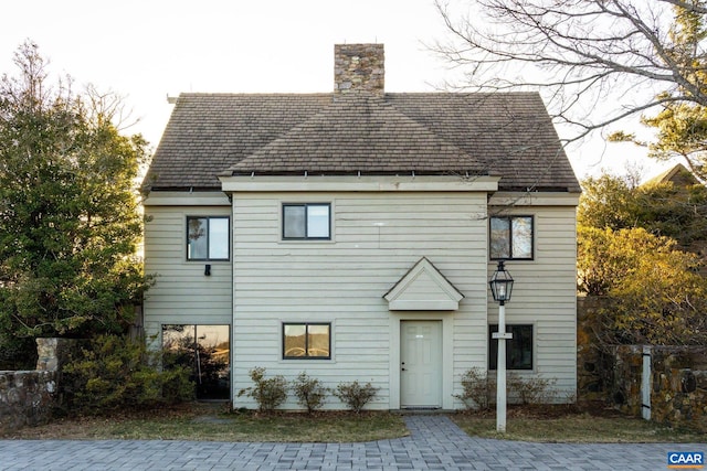 view of front of home with a shingled roof and a chimney