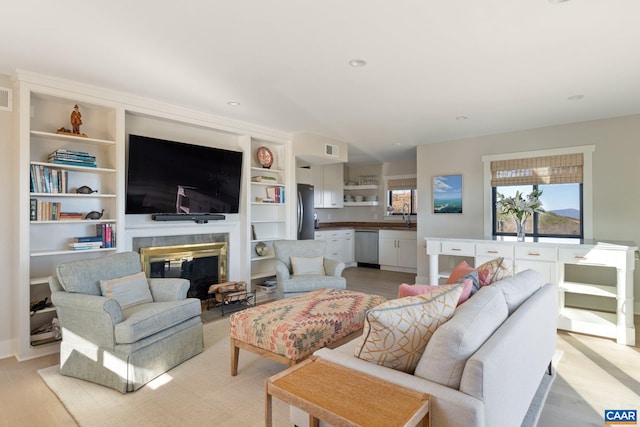 living area featuring visible vents, recessed lighting, light wood-type flooring, and a premium fireplace