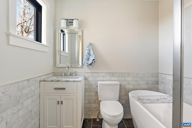 bathroom featuring tile patterned flooring, wainscoting, vanity, and a freestanding tub