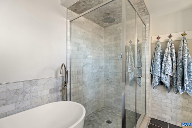 full bath featuring a soaking tub, a shower stall, and tile walls