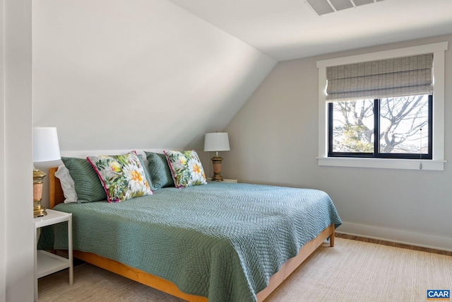 bedroom with vaulted ceiling, wood finished floors, visible vents, and baseboards