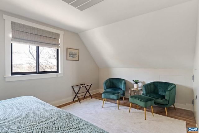 bedroom with vaulted ceiling, wood finished floors, and baseboards