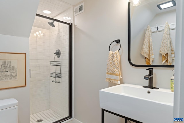 bathroom with visible vents, a shower stall, toilet, and a sink