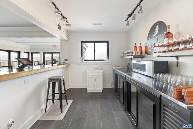 bar with a sink, bar, and rail lighting