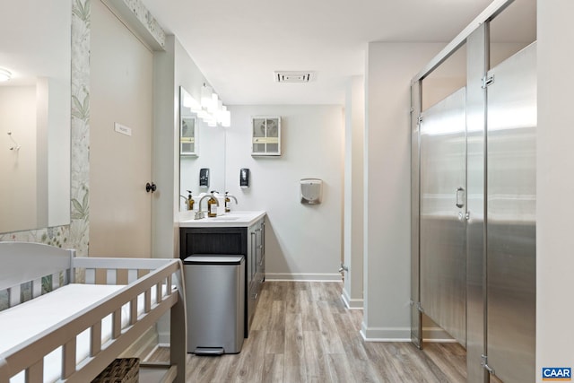 full bathroom featuring vanity, wood finished floors, visible vents, baseboards, and a shower stall