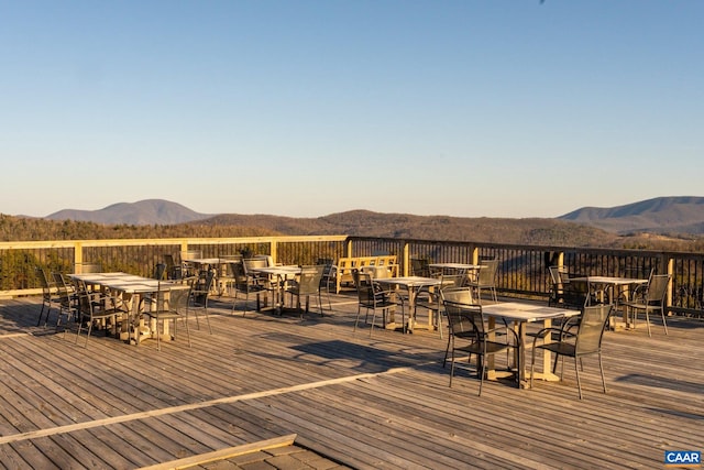 deck with outdoor dining space and a mountain view