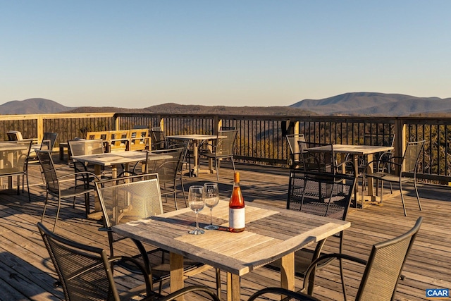 wooden terrace with outdoor dining space and a mountain view