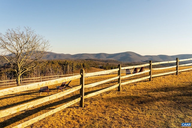 view of yard featuring a rural view, fence, and a mountain view