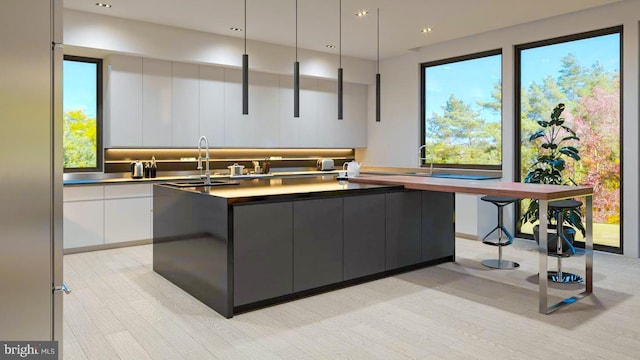 kitchen with a kitchen island, a sink, white cabinetry, modern cabinets, and light wood-type flooring