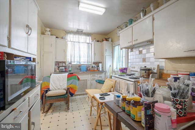 kitchen with white electric range oven, light floors, and white cabinets