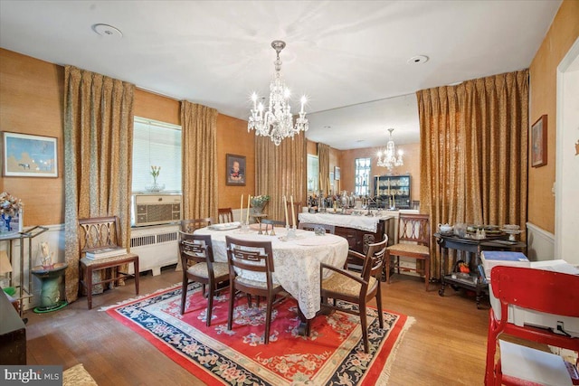 dining room featuring a chandelier, radiator, light wood-type flooring, and a healthy amount of sunlight