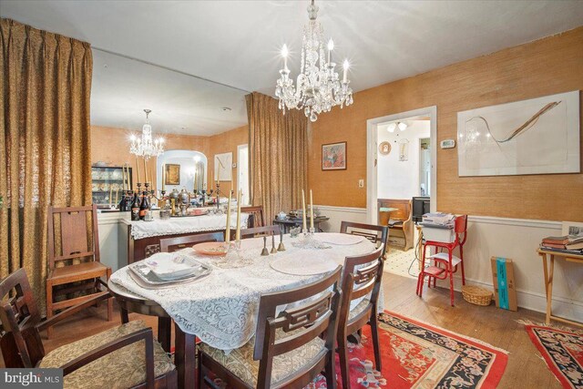 dining space featuring a chandelier, wood finished floors, and wainscoting