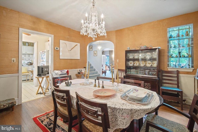 dining space with stairway, arched walkways, hardwood / wood-style floors, and a notable chandelier
