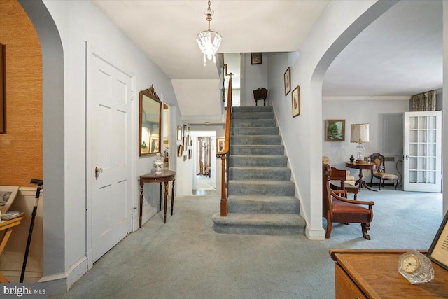 stairway featuring arched walkways, baseboards, and carpet floors
