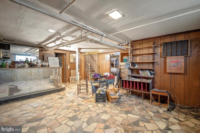 basement featuring wood walls, stairs, and stone flooring