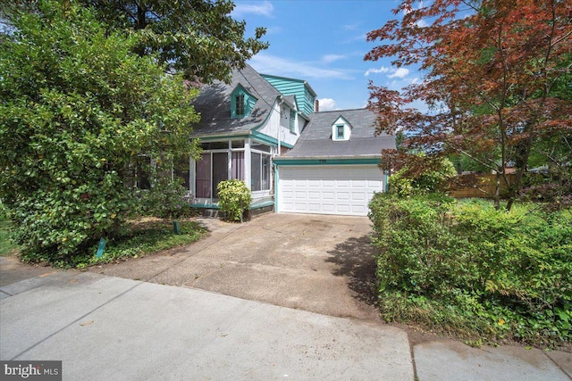 view of front of house featuring a sunroom, concrete driveway, and an attached garage