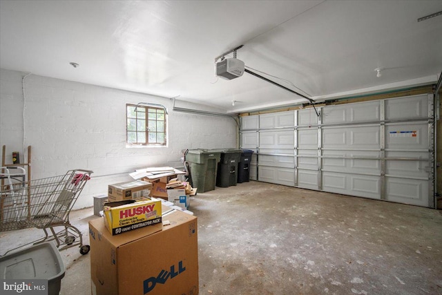 garage featuring concrete block wall and a garage door opener