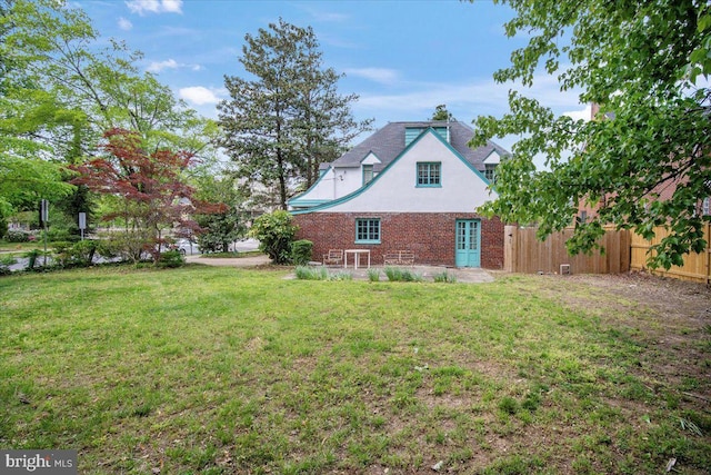 exterior space featuring a yard, fence, french doors, and brick siding