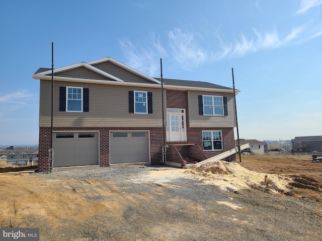 split foyer home featuring an attached garage, brick siding, and driveway